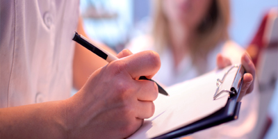 Close up of doctor writing on a medical chart. Close up of doctor writing on a medical chart.