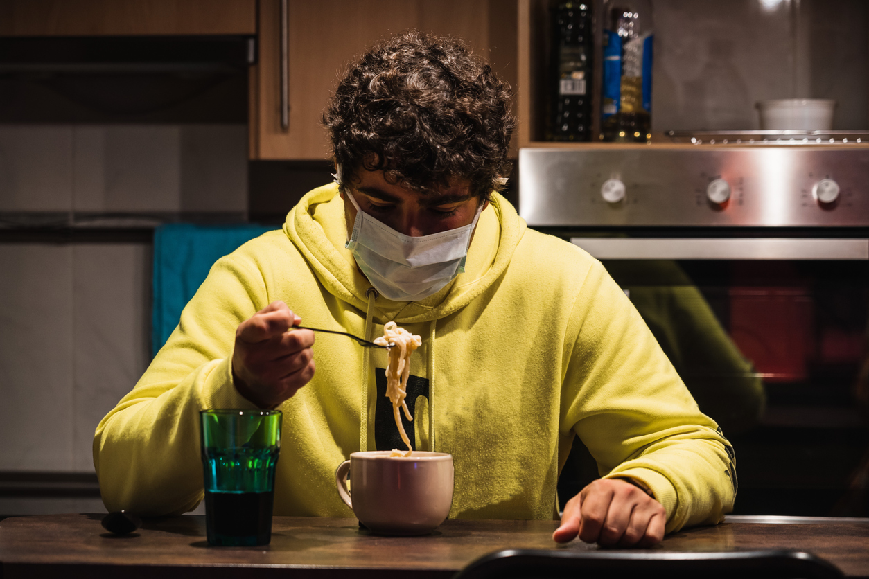 Young spanish man tries to eat wearing a mask while wearing a mask protecting to coronavirus COVID-19 due to hysteria and panic caused by media and governments a very contagious virus Young spanish man tries to eat wearing a mask