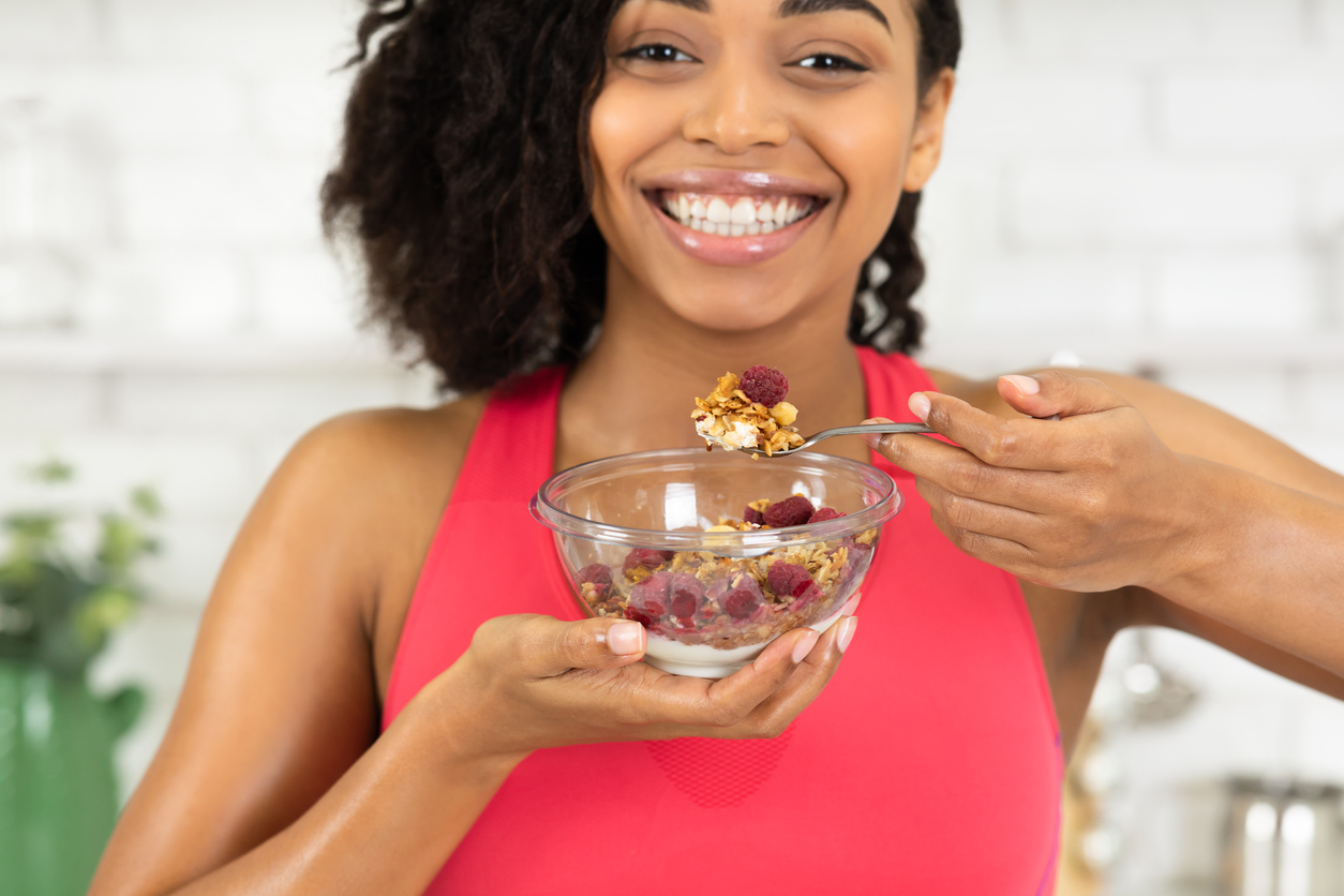 Black girl eating granola with yogurt in bowl Black girl eating granola with yogurt in bowl